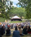 Stort publikum sidder på græsset foran Amfiscenen under PARK Vidensfestival.